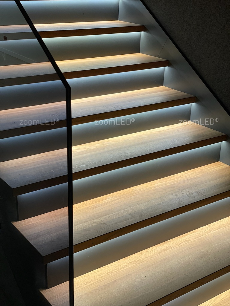 Pasek led umiejscowiony pod stopniem na schodach oświetlający cała powierzchnię
