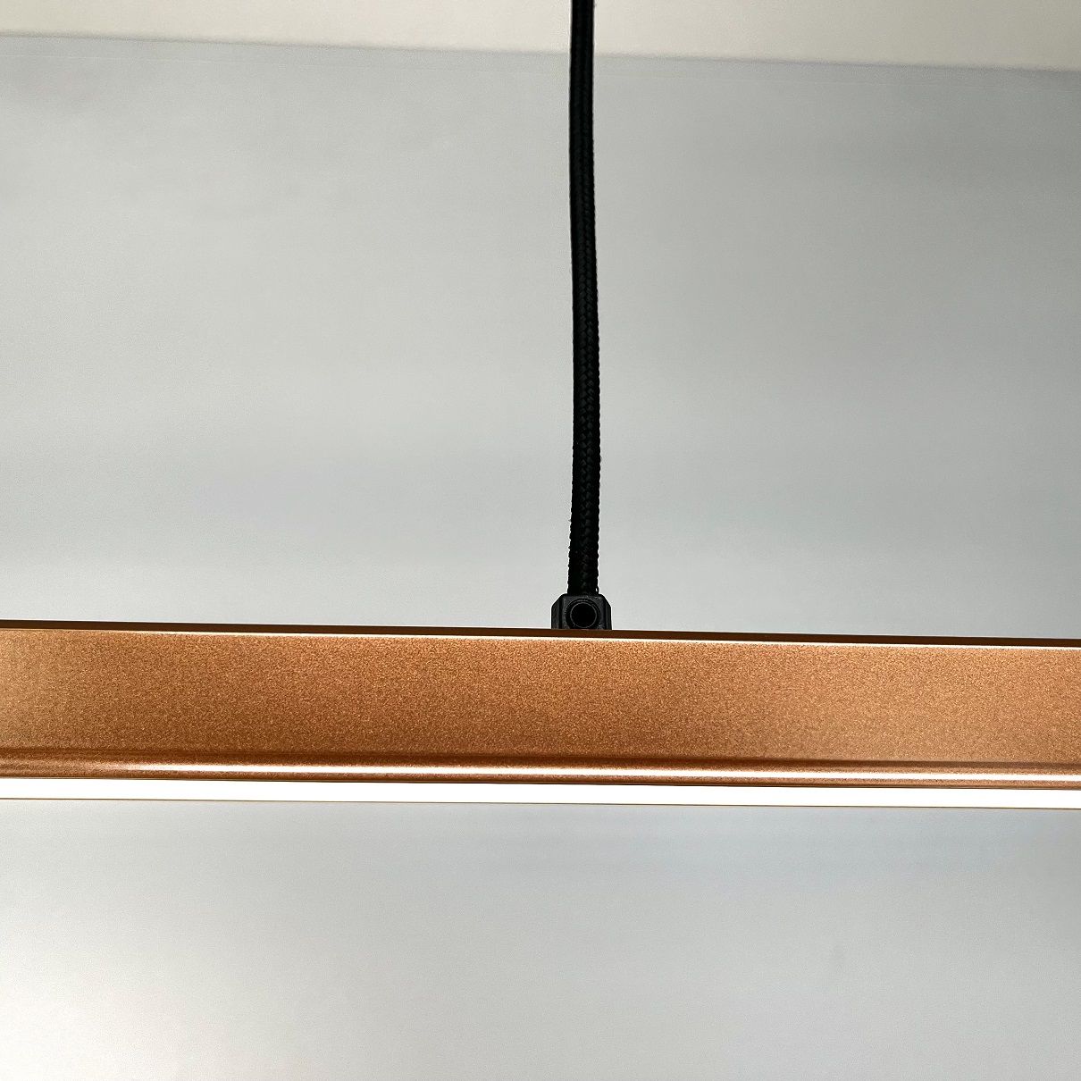 Lampa wisząca liniowa w kolorze różowego złota z bliska element mocowania