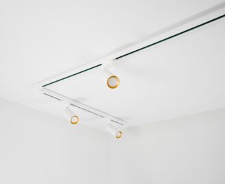 Trzy białe ruchome reflektory ze złotym środkiem zamontowane na szynoprzewodzie