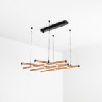 Lampa wisząca składająca się z kilku prostych tub w kolorze miedzianym ułożonych poziomo